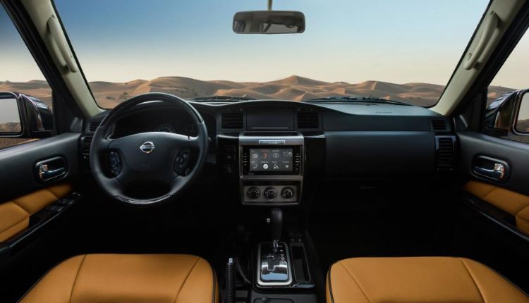 صورة تظهر المقصورة الداخلية لسيارة نيسان سوبر باترول بها عداد السرعة وعجلة المقود وشاشة عرض معلومات